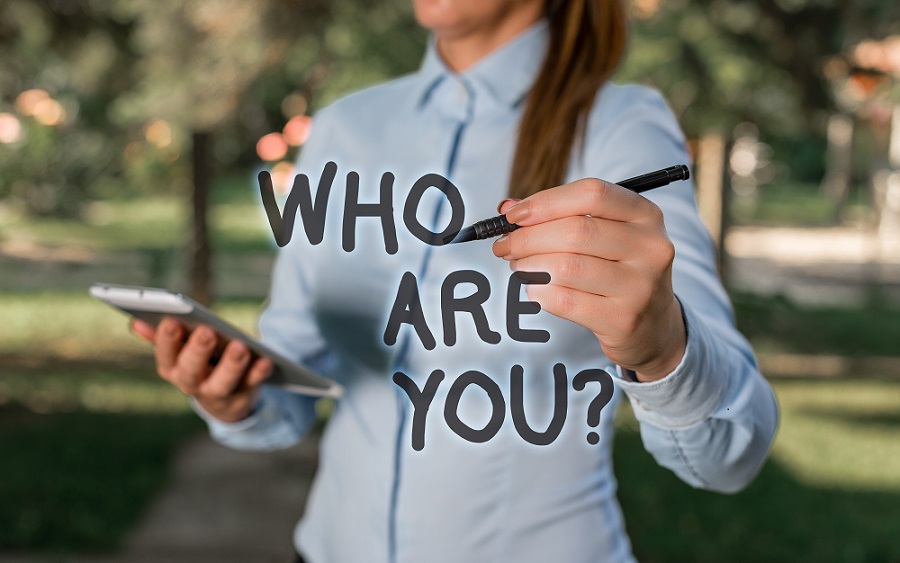 Nainen kirjoittaa läpinäkyvälle taululle tekstin Who are You?